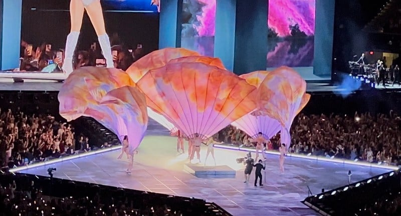 Several dancers holding bright-colored parachutes formed a flower shape on stage.