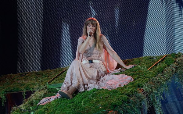 Taylor Swift singing on the roof of a moss-covered cabin.