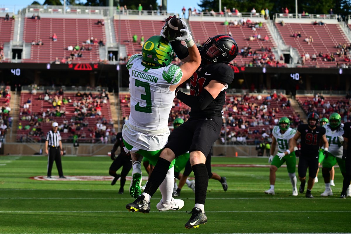 An Oregon and Stanford player both grab onto the ball in the air.