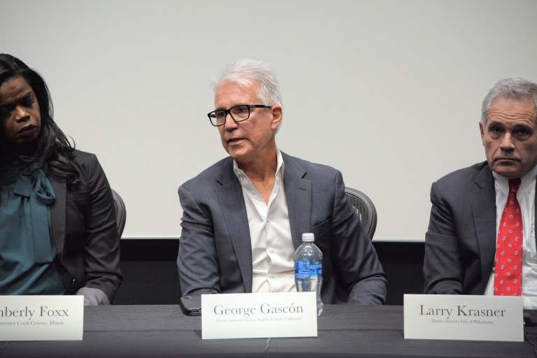 A professor sits on a panel with a name tag.