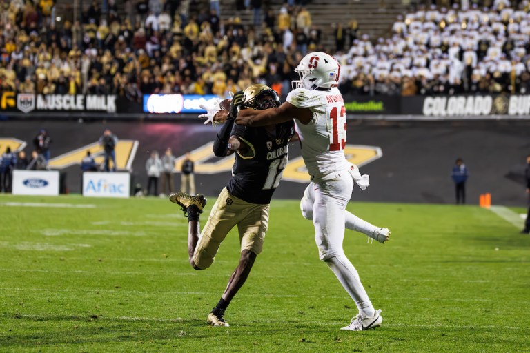 Two football players collide on the field, one in a blue and yellow uniform and the other in a red and white one.