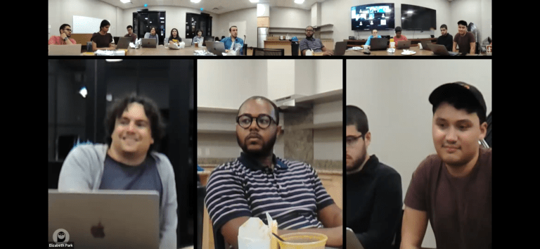 Screenshot of people sitting around a desk having a meeting