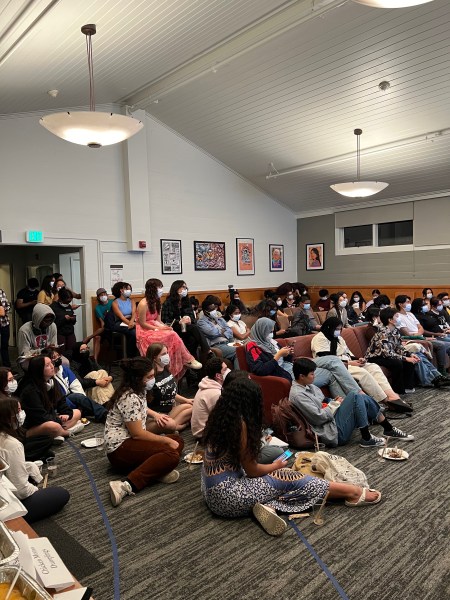 Students gathered in the Okada lounge sitting on the floor and chairs.