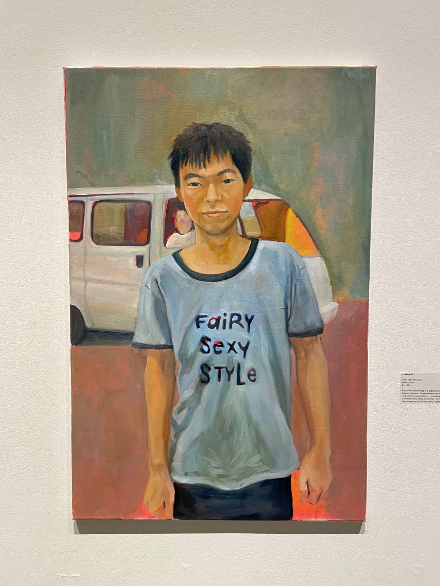 A photo of an oil painting of a man wearing a blue shirt that says "Fairy Sexy Style." The man stares straight ahead. In the background is a white van.