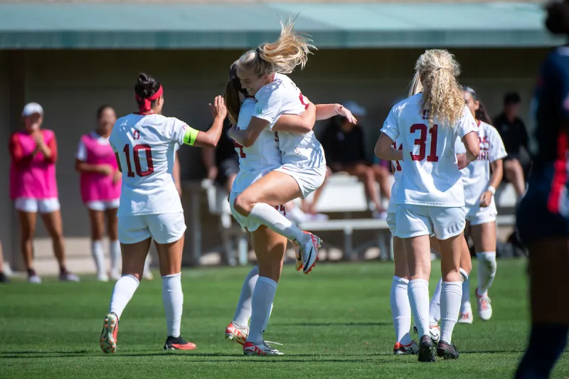 Stanford women's soccer players jump against each other in celebration during a game against University of Arizona.