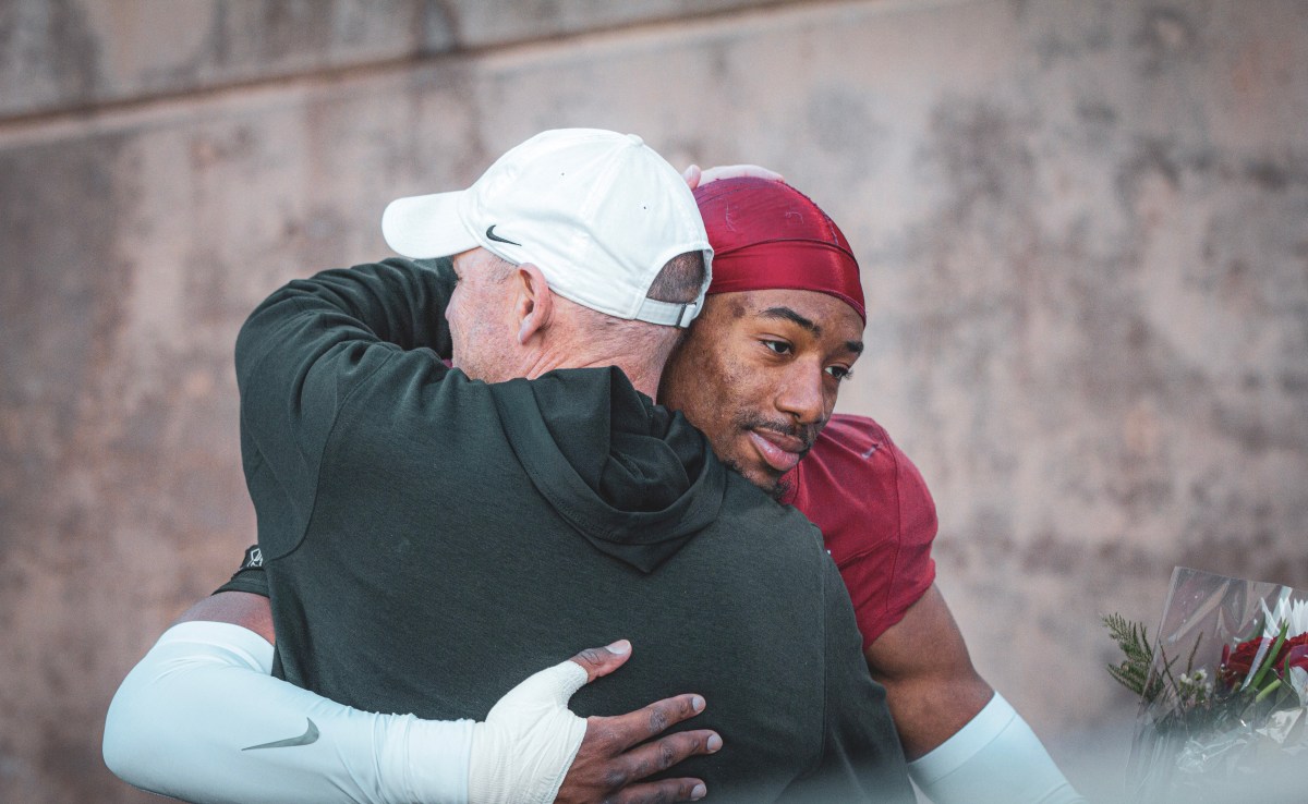 A Stanford player hugs a man in a hoodie.