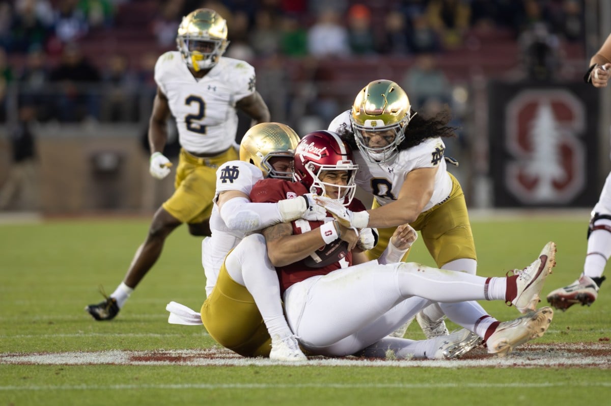Stanford's quarterback getting tackled by two Notre Dame players