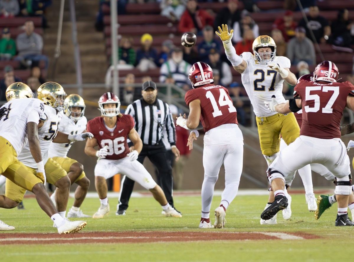 Stanford's quarterback throws the ball past Notre Dame defenders to a waiting receiver.