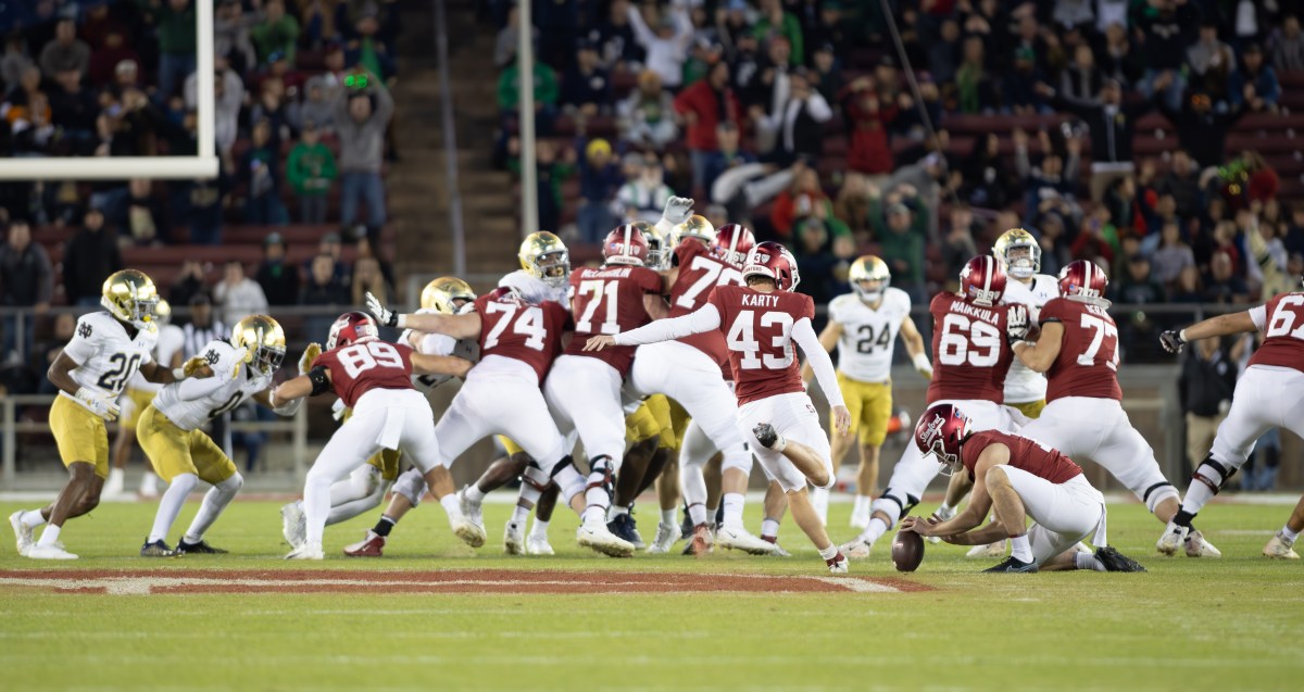 Stanford's kicker winds up for a 56-yard field goal attempt while the offensive and defensive lines collide.