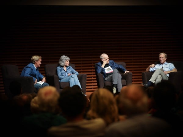 James Steyer, Jane Fonda, Bill McKibben and Tom Steyer seated on the stage at Cemex auditorium. Each wear business casual in shades of blue, and McKibben is wearing a shirt with the California flag. In the foreground are out of focus audience members.