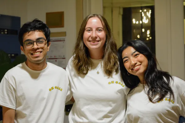 Three college students smile wearing "On Call Cafe" t shirts