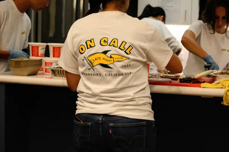 a photo of a student facing away from the camera; they are wearing a t-shirt that reads "on call" in bold yellow letters, above a yellow pennant logo
