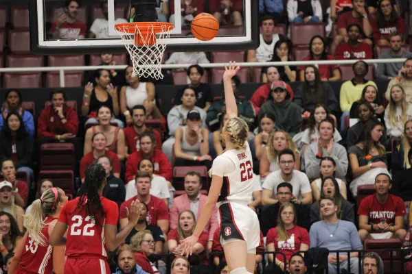 A Stanford basketball player reaches up for the ball mid-air, with two rival players beneath her.