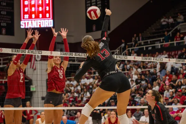 Sophomore outside hitter, Elia Rubin, hits against two Washington State blockers. (Photo: ETHAN FUNG/The Stanford Daily)