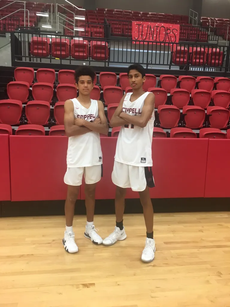 Ryan Agarwal and Anthony Black stand in front of bleachers with their arms crossed.