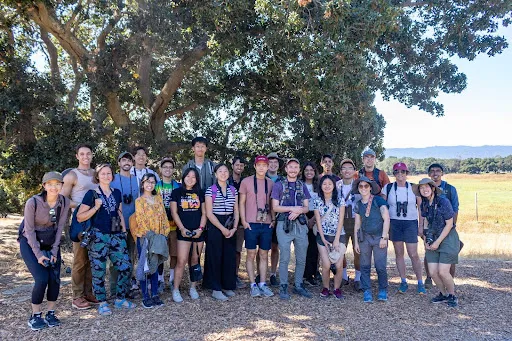 Members of the Stanford Birdwatching Club crowd together for a picture at Lake Lagunita.