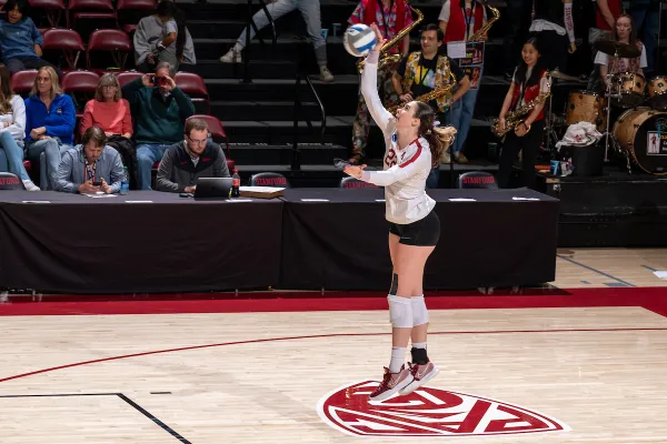 A Stanford player prepares to serve by holding the ball aloft with one hand.