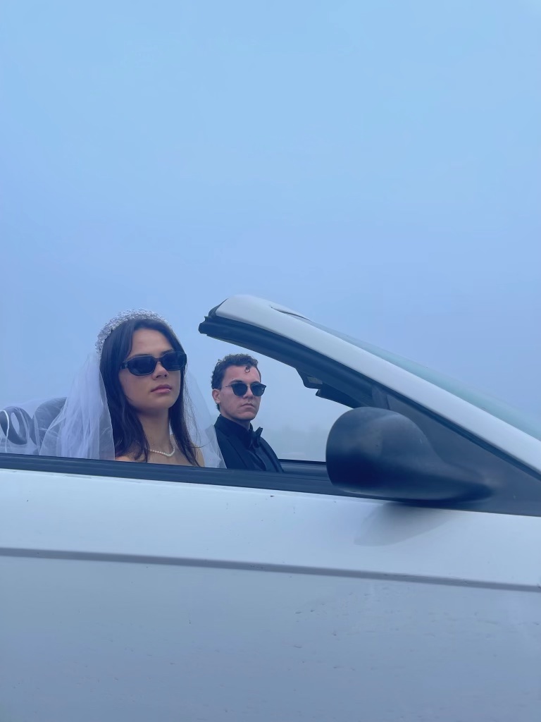 Two FashionX models drive in a convertible in a foggy Main Quad