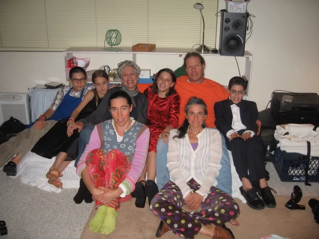 Black and other members of the cult he was in sit on the floor of a living room, surrounding his father.
