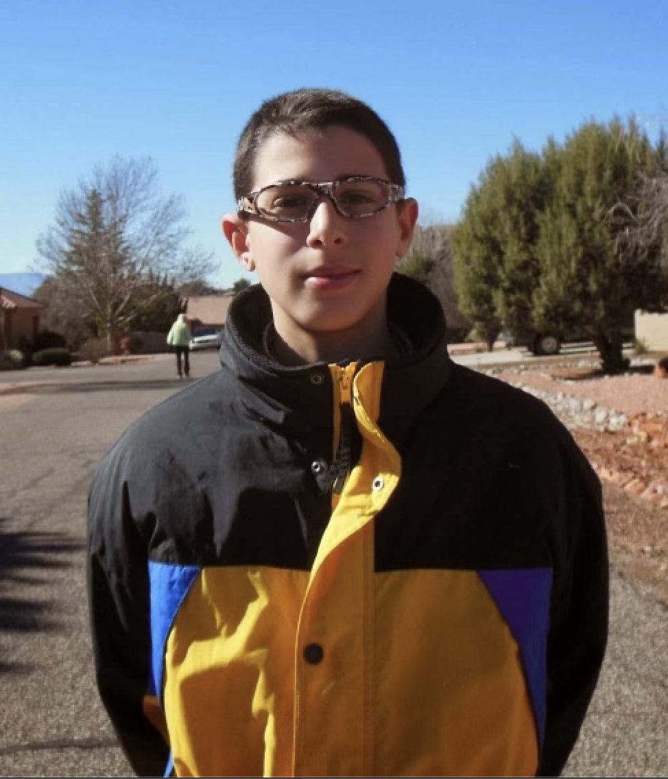 A 13-year-old Black stands outside in a yellow winter jacket with it's lining cut open to conceal heroin.