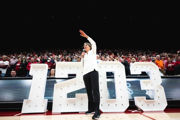 Tara VanDerveer stands in front of a 1203 sign as the crowd behind her cheers.