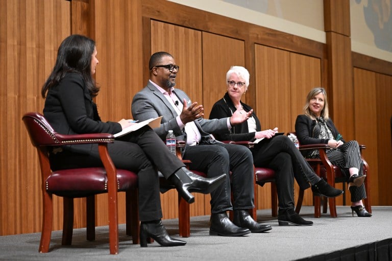 Four people sit in a row on a stage