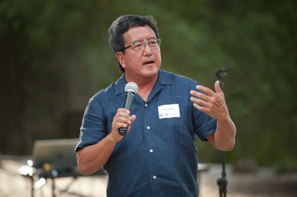 Peter Ohtaki speaks into a microphone outside.