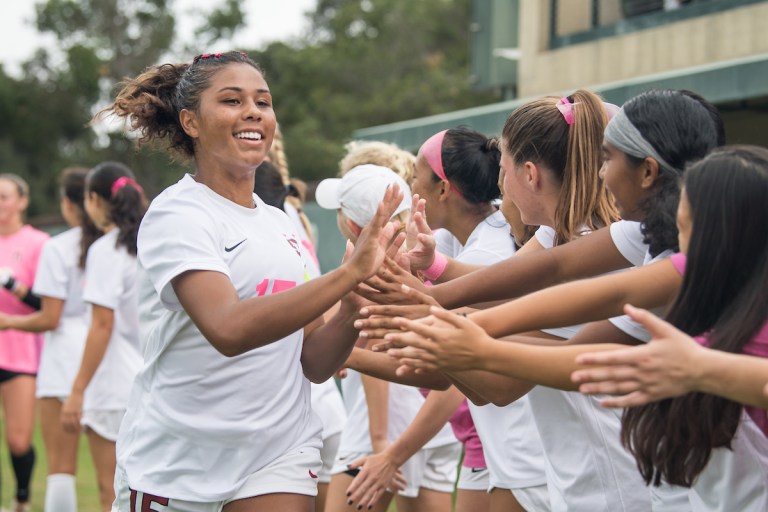 Kennedy Wesley smiles at the camera as she shakes hands with her teammates.