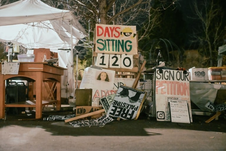 A sign that reads 120 days sitting surrounded by pro-Palestine posters and tents.