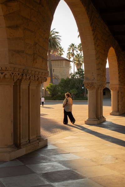 A man walks through the arches in Stanford's Main Quad.