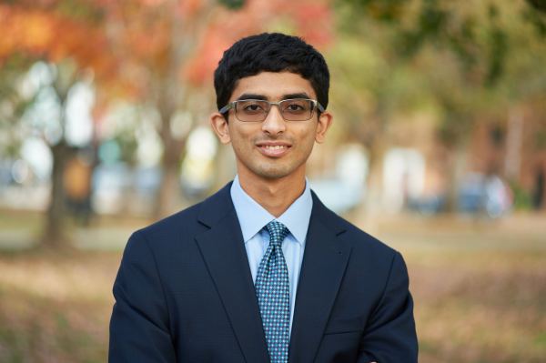 Ashwin Ramaswami ’21 poses in front of fall foliage wearing tinted glasses and a suit and tie.