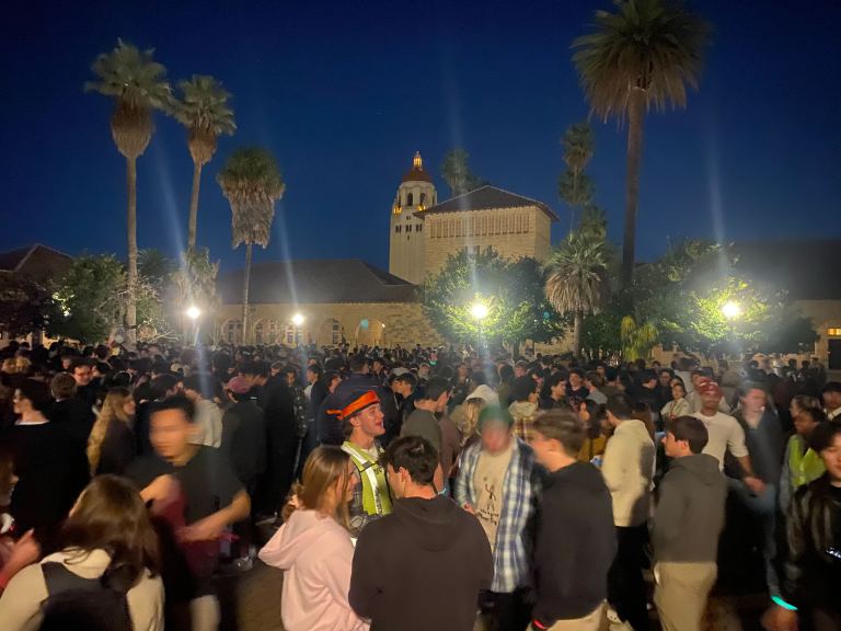 A crowd gathers in the well-lit Main Quad