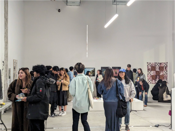 Students walk around a wide-open, white art gallery