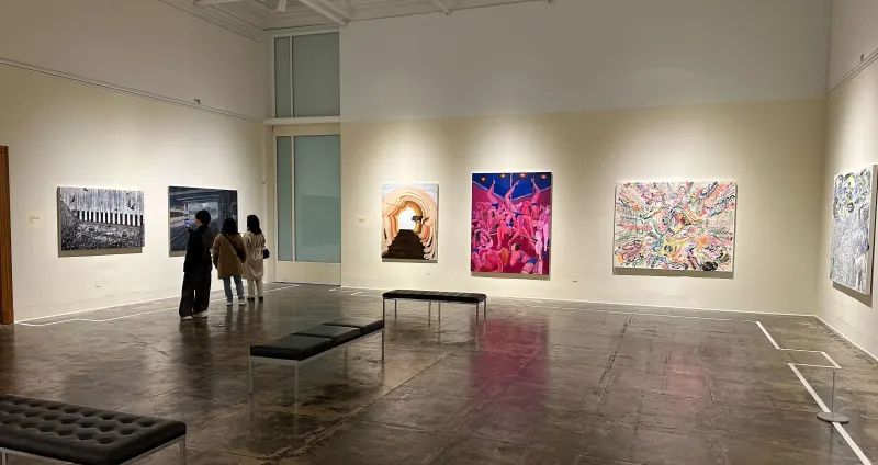 a white-walled art gallery with large, brightly colored paintings