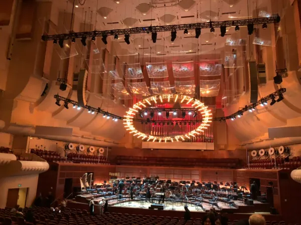 The stage set-up for the SF Symphony performance at Davis Hall includes a ring of lights shining upon the ensemble from above.