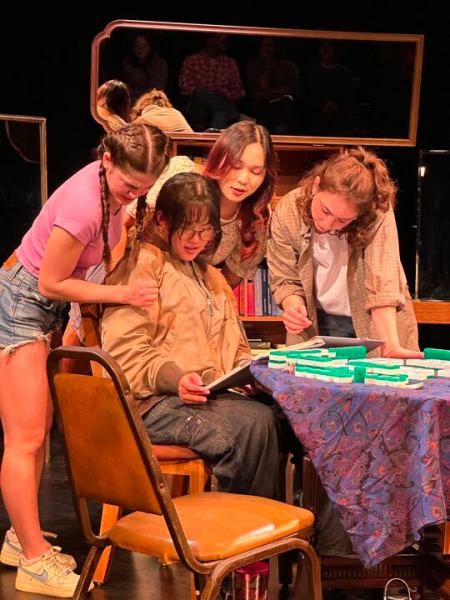 Four students gather around one sitting at a mahjong table in the play "Yakuman Chance"