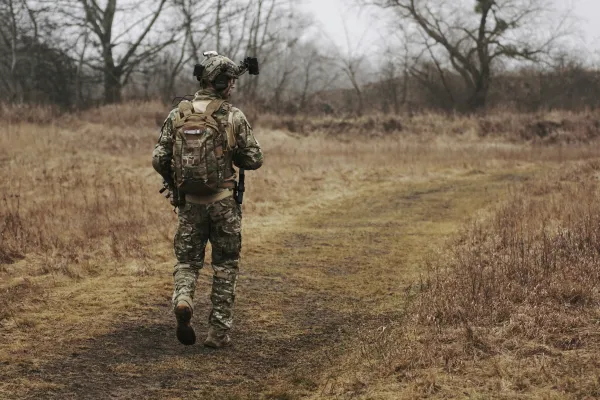 The back of a soldier in uniform walking down a path