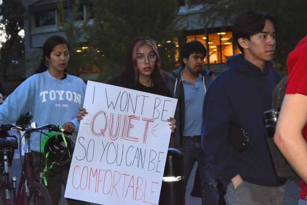 A student holds a sign that says, "I won't be quiet so you can be comfortable," at Take Back The Night.