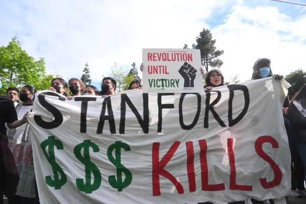 Protestors hold a banner that reads Stanford $$$ kills.