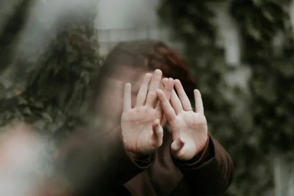 a woman hiding from the camera by putting her hands in front of her