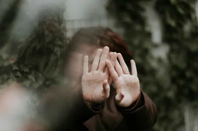 a woman hiding from the camera by putting her hands in front of her