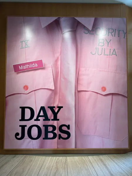 A large painting of a pink button-up shirt and tie with "Security by Julia" and a nametag attached to the shirt. The words "Day Jobs" is written across the bottom of the canvas.
