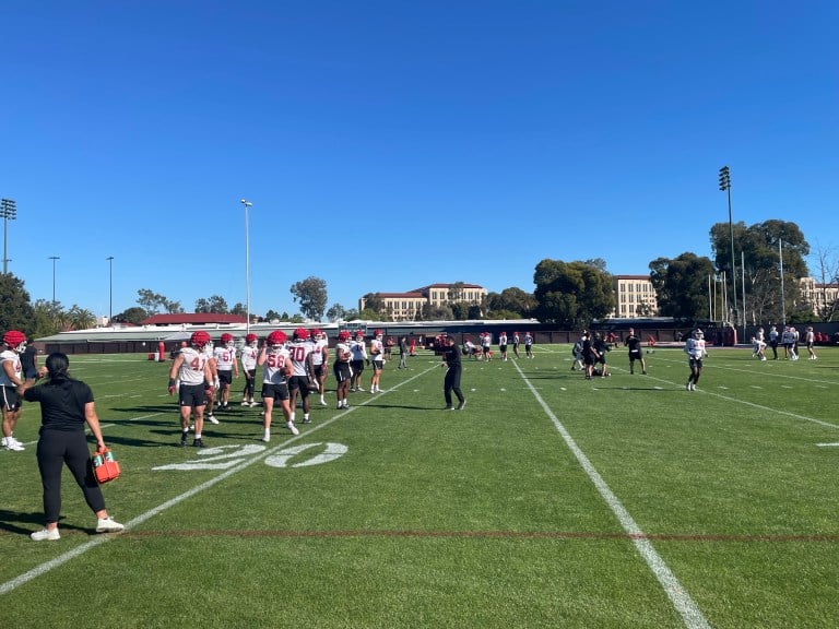 Stanford players gather on the field on a sunny day.