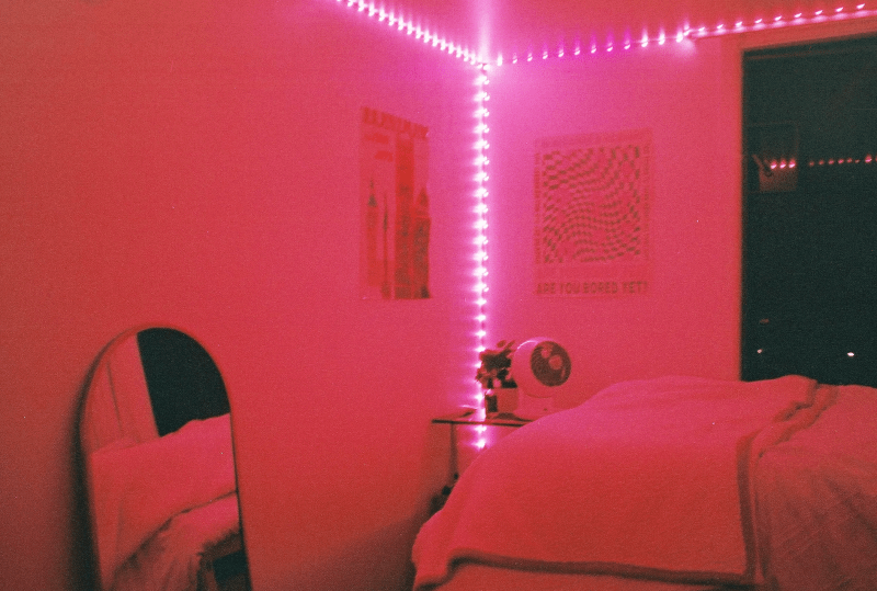 A corner of a dorm room with bright pink LED lights