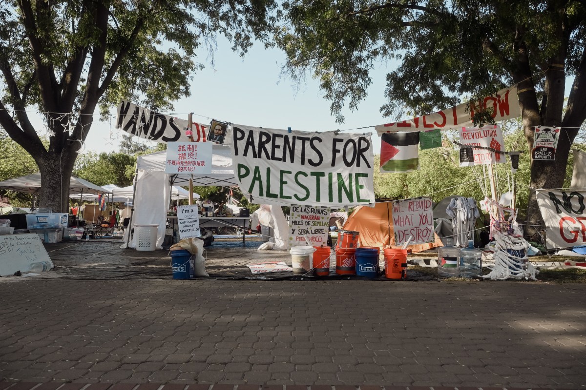 A sign that reads Parents for Palestine hangs. Tents visible in the background.