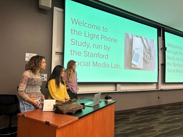 Study authors from the Stanford Social Media Lab presenting slides about the Light Phone in a classroom.