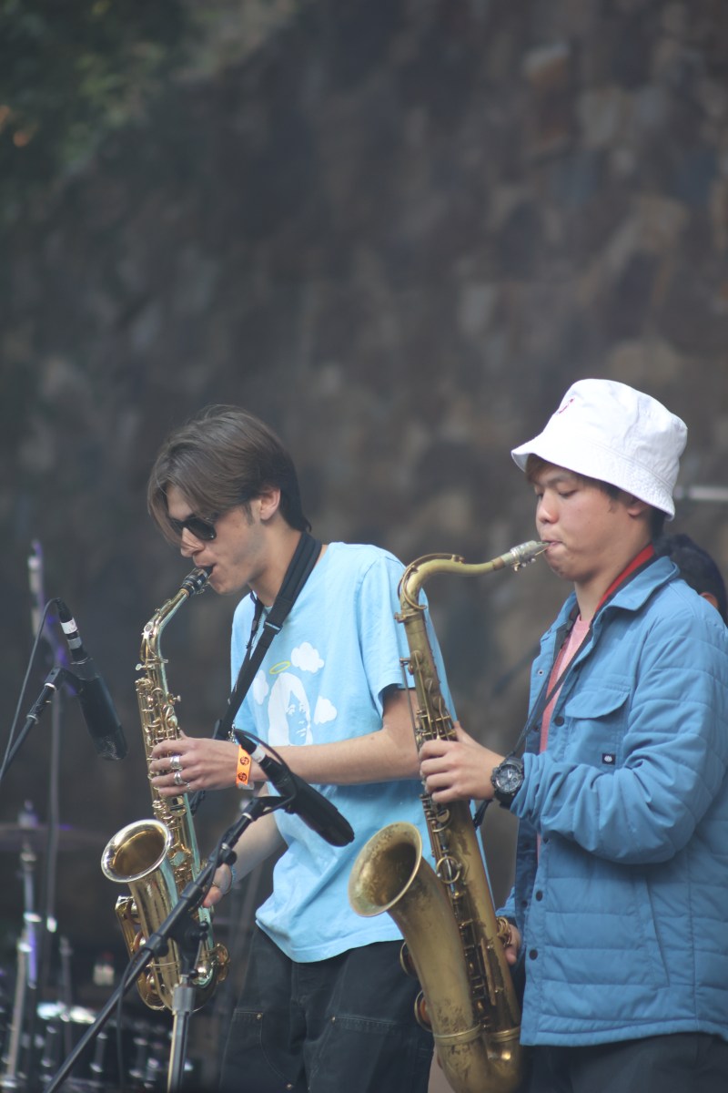 Two students play the saxphone on a stage.