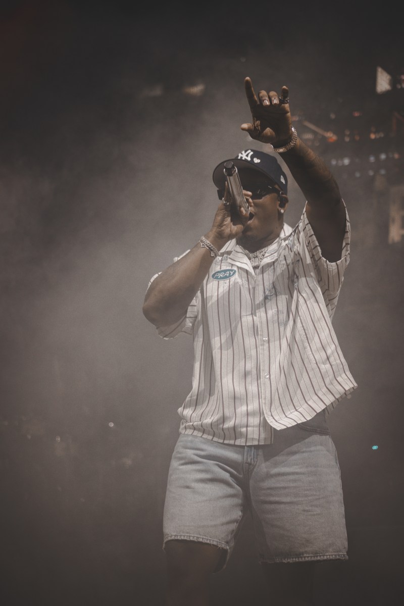 A performer raps surrounded by smoke and in a white striped shirt with a patch that reads "pray."