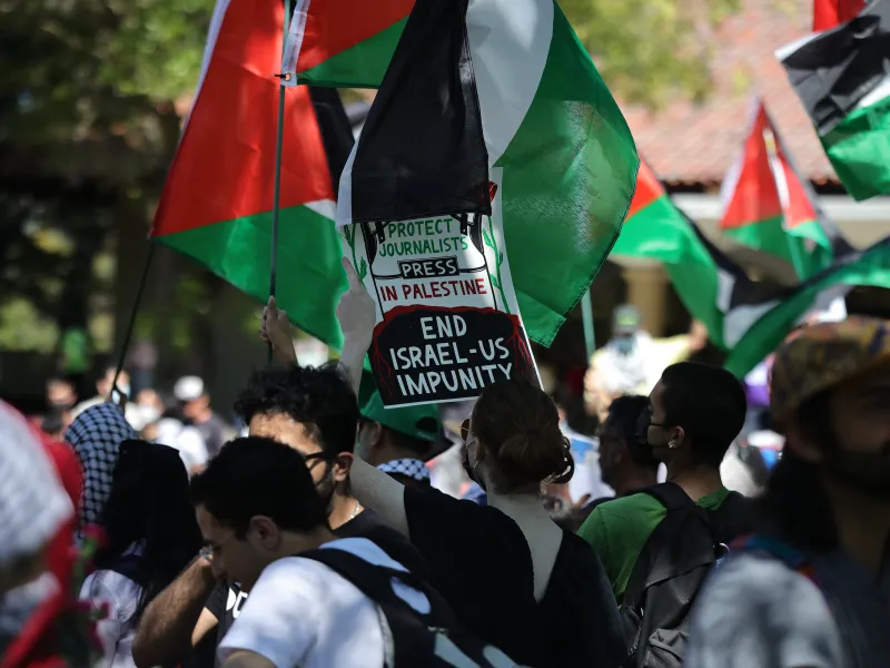 Protestors hold up Palestinian flags.