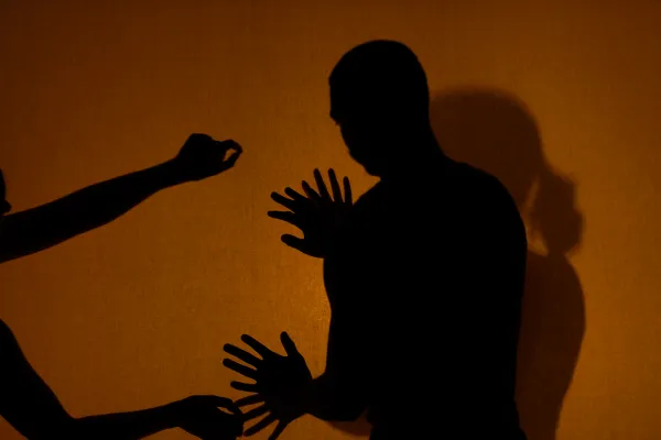 Photo from the Box of Sand performance, two silhouettes and a pair of hands show on an orange background.